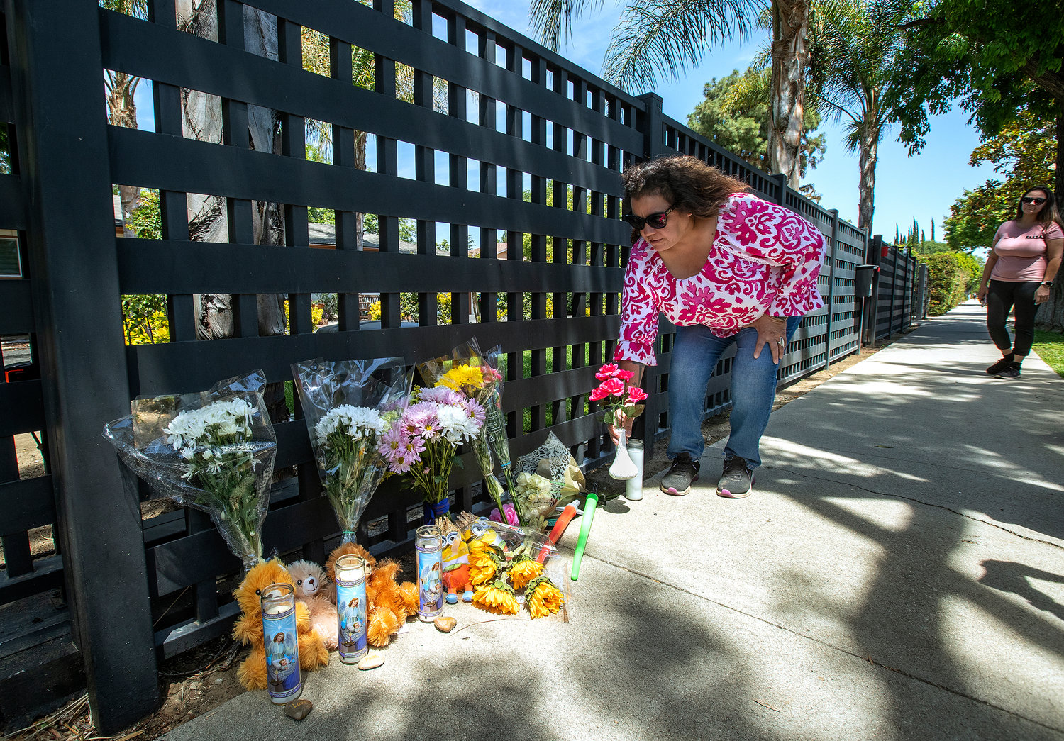 Lupeann Campos of Winnetka, California, places flowers at a memorial in front of a home on Victory Boulevard in West Hills. Three children were found dead inside the residence Sunday, May 8, 2022. (Mel Melcon/Los Angeles Times/TNS)